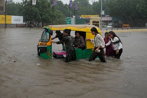 People wade an auto through the flooded roads in Gujarat |